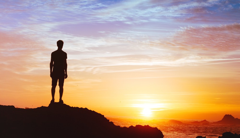 Man on cliff looking at sunrise
